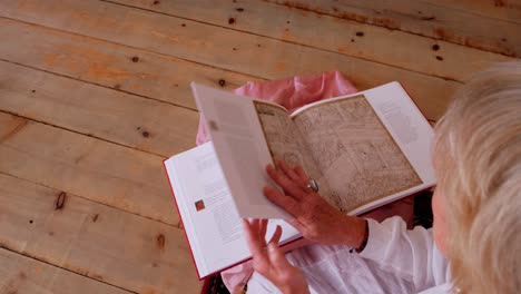 Vista-Por-Encima-Del-Hombro-De-Una-Mujer-Rubia-Leyendo-Un-Libro,-Primer-Plano-De-Pasar-Páginas