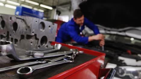 car parts with tools and mechanic working in background