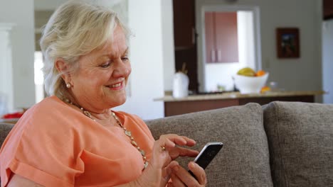 mujer mayor usando teléfono móvil en la sala de estar 4k