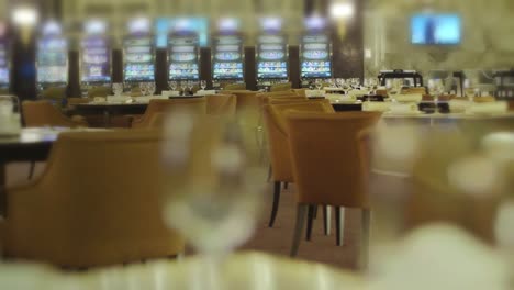 empty tables with wine glasses in restaurant near slot machines in casino