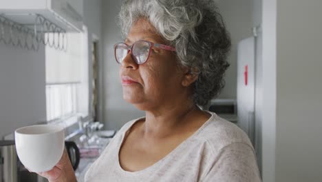 a senior african american woman spending time at home holding a cup. social distancing in quarantine