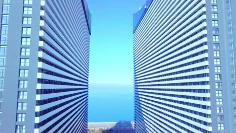 the drone flies between two buildings with glass windows.