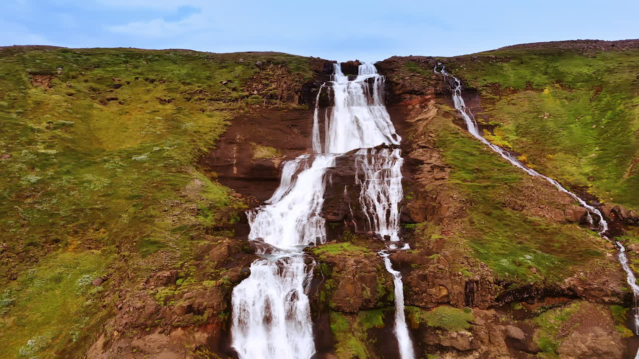 Big and small waterfall descending from the bare rock covered with moss. Splendid wild nature of Iceland.