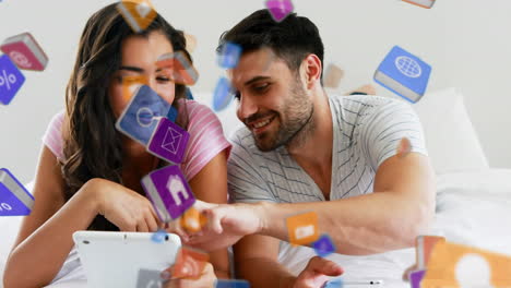 multiple digital icons floating against man and woman using digital tablet and smartphone at home