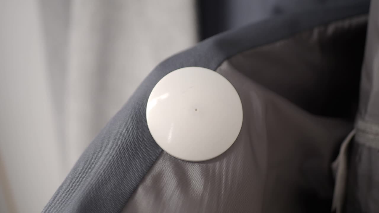 En hvit sikkerhetsbrikke på et grått stoff