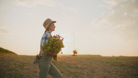 mujer agricultora caminando por un campo al atardecer con un ramo de flores