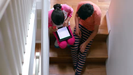 Kids-using-digital-tablet-while-sitting-on-the-staircase-4k