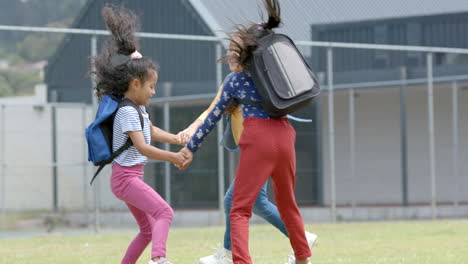 in school, three young biracial girls holding hands, spinning around