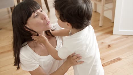 mamá alegre abrazando, acurrucando y besando al dulce niño