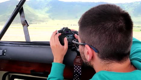 young traveler checking camera photos during a 4x4 safari trip in tanzania, africa