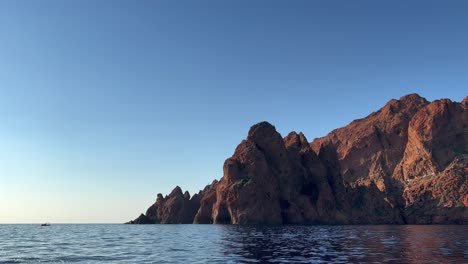 headland of scandola peninsula nature reserve in summer season as seen from moving boat, corsica island in france