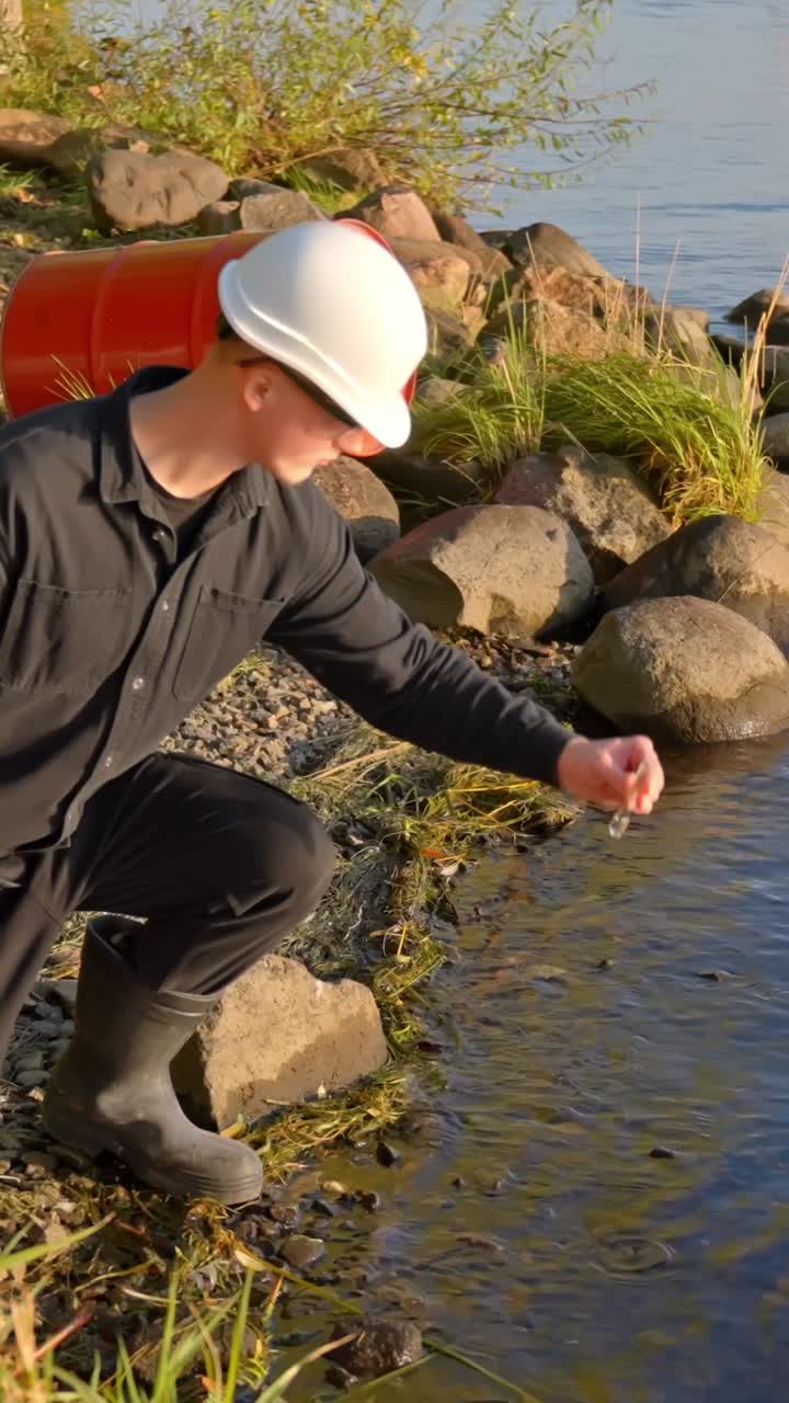 Technician crouching by river collecting water sample in vertical shot