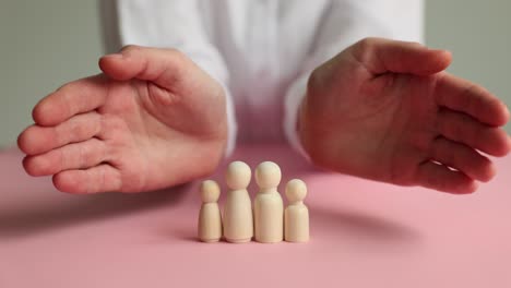 hands protecting wooden family figures