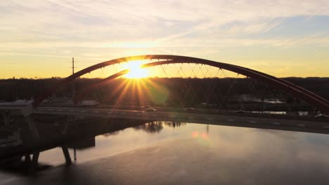 dramatic aerial view of hastings bridge as the sun hits the horizon in the background and creates a starburst flare effect in the camera lens