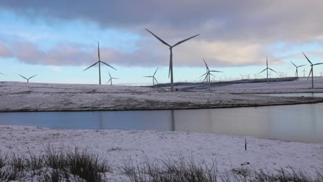 Wind-turbines-spin-on-a-windy-day,-looking-out-over-Lochgoin-Reservoir-at-Whitelee-Windfarm