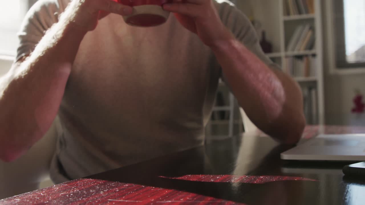 사회적 거리를 두는 백인 남성이 집에서 커피를 마시고 있습니다.