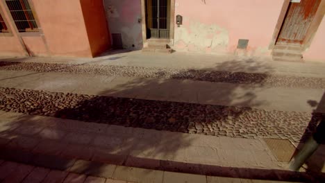 Stone-and-cobblestone-street-near-majestic-historical-colorful-buildings-in-Sardinia-island