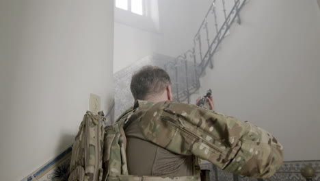 medium shot of a focused soldier with scratches on face looking up and climbing stairs