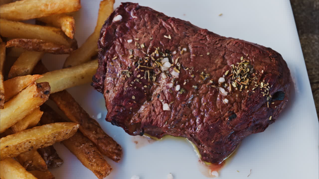 Close up of stake with fries and salad on a white plate at a restaurant
