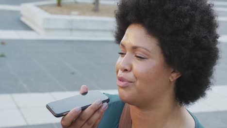 Happy-plus-size-biracial-woman-talking-on-smartphone-in-city