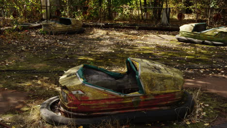 Broken-and-overgrown-bump-cars-in-Pripyat-amusement-park,-pan-right-view