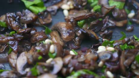 mushrooms frying in a pan with pine nuts and parsley