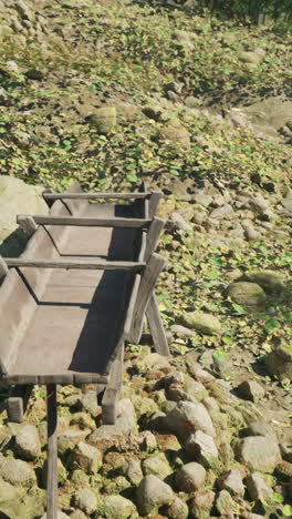 a wooden trough sits on a bed of stones in a forest setting