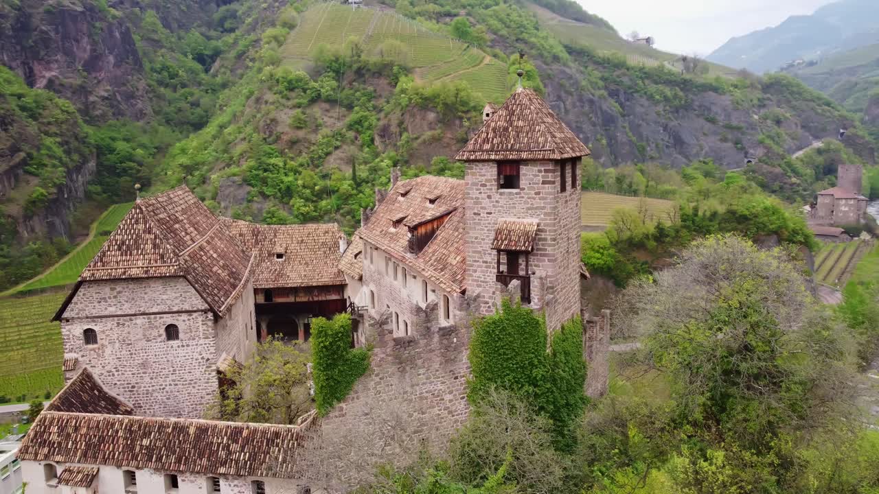 Medieval stone castle with tower overlooking vineyard and mountain river, location historical tourist attraction