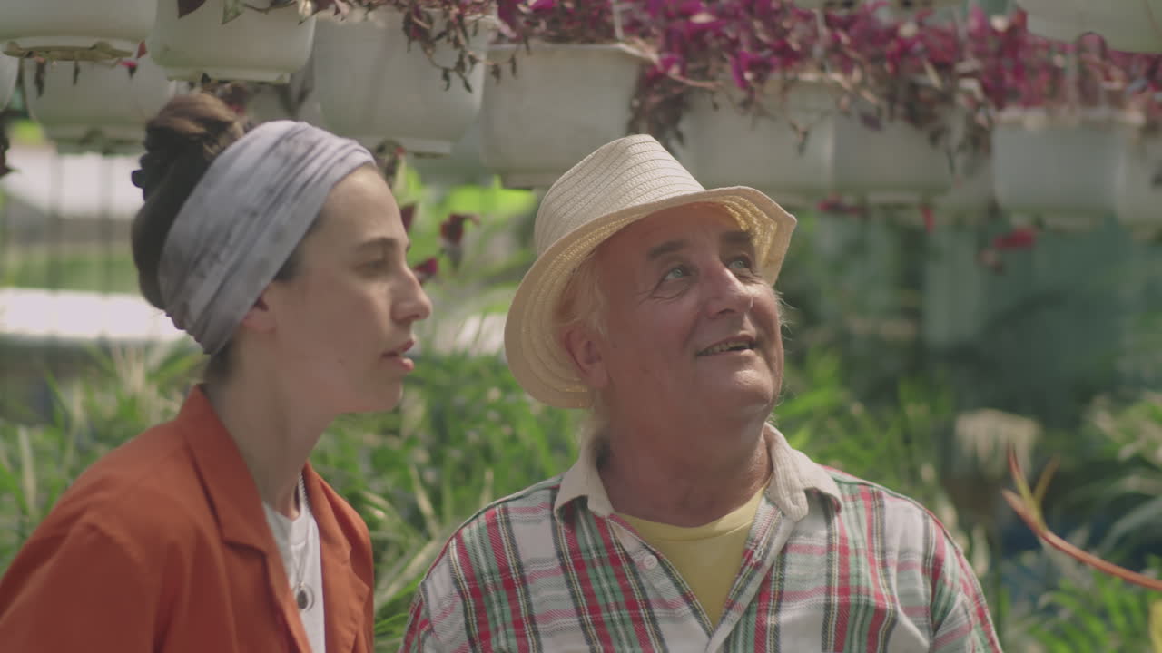 Coworkers Discussing and Pruning Flowers in Plant Nursery