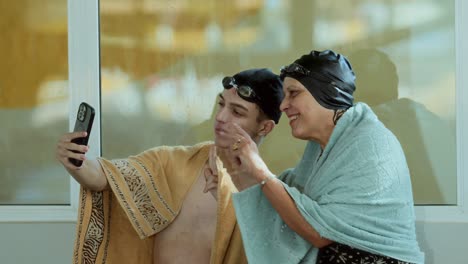 Two swimmers in towels taking a selfie after a swim