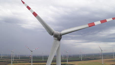 Revolving-high-tech-wind-turbine-delivering-energy-generation-aerial-drone-shot-surrounding-wind-farm