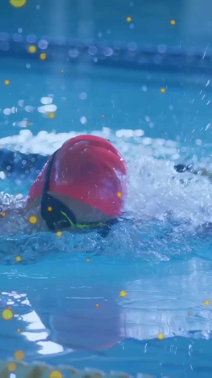 Video vertical: Mujer nadadora entrenando estilo libre en la piscina, salpicadura al entrar el brazo, superposición amarilla.