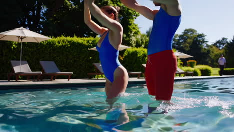 couple enjoying a fun water workout at a resort pool