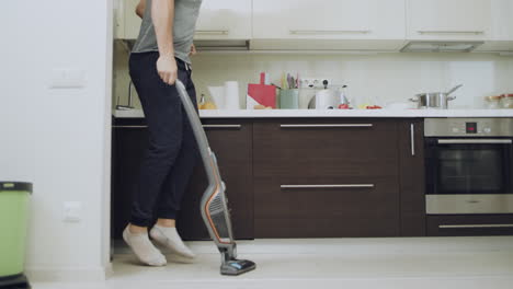 happy man cleaning floor at kitchen. joyful guy jumping with vacuum cleaner