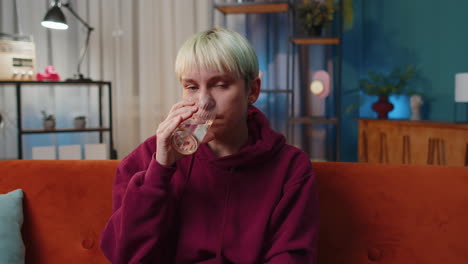 smiling woman drinking water on a couch