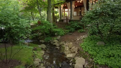 beautiful lush green landscaping and flowing stream leading to an upscale luxury restaurant with flowing curtains