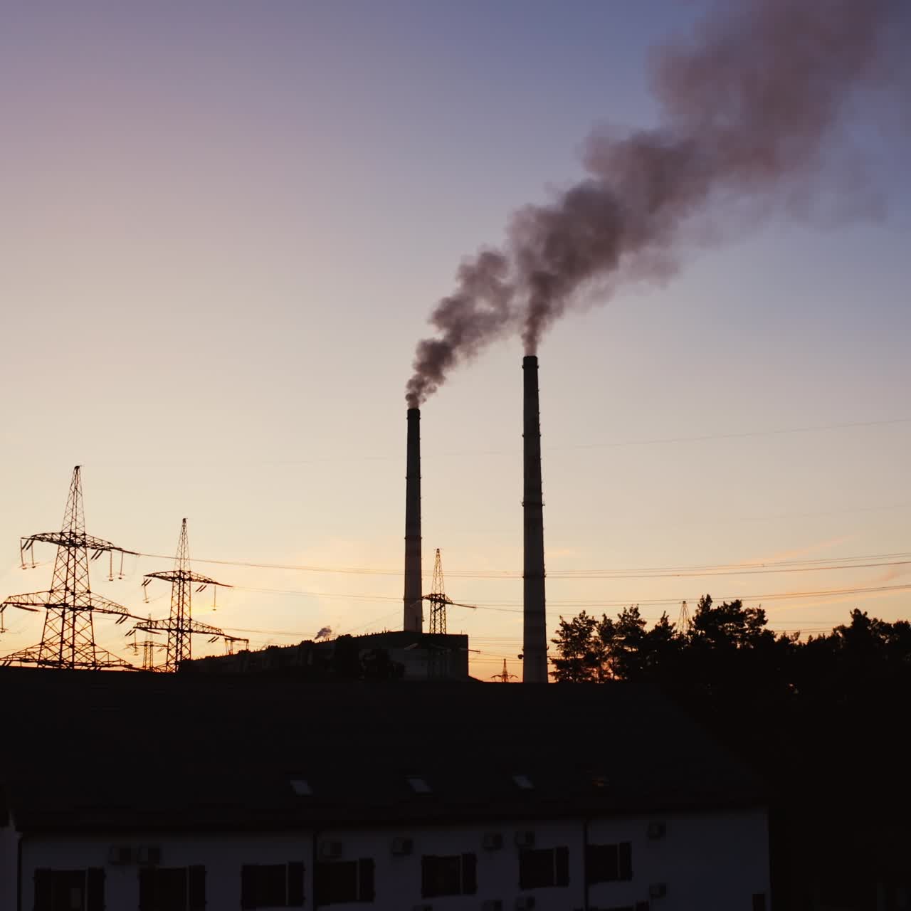Industrial pipes of the thermal power plant at sunset. Smoke from the factory chimneys against the evening sky. The concept of environmental pollution.