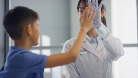 asian female doctor giving high five to kid