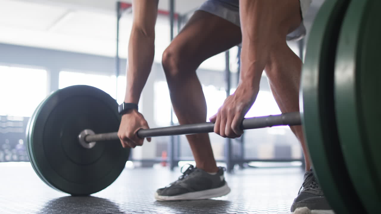Lifting barbell, man exercising in gym, focusing on strength training