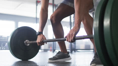 lifting barbell, man exercising in gym, focusing on strength training