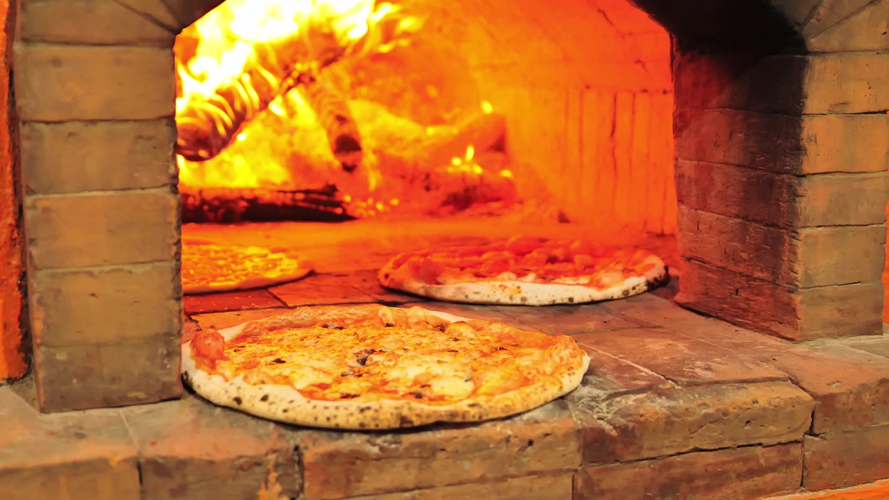 Pizza fresca in cottura all'interno di un tradizionale forno a legna in mattoni.