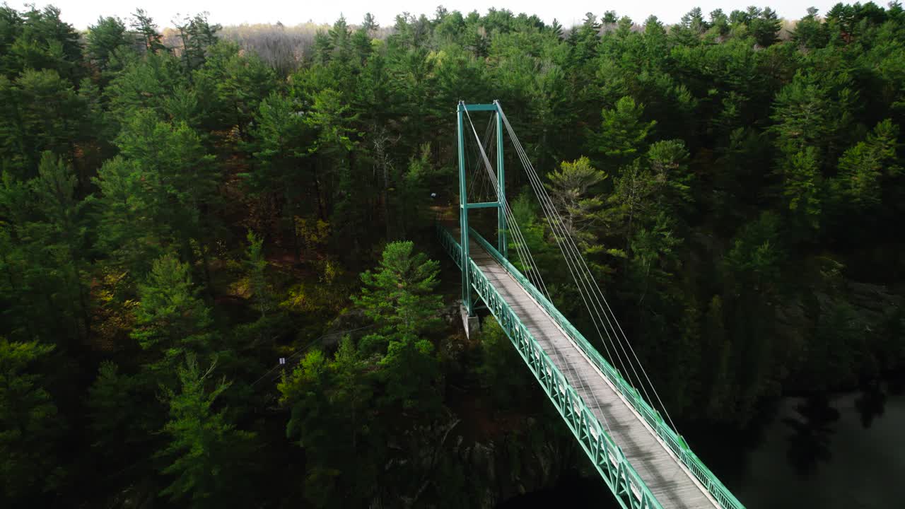 puente colgante peatonal de motos de nieve sobre el cruce del río francés en un día soleado junto a un acantilado rocoso