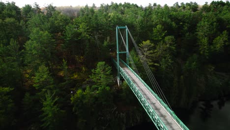 Pedestrian-Snowmobile-Suspension-Bridge-over-French-River-crossing-on-a-Sunny-day-next-to-rocky-cliff