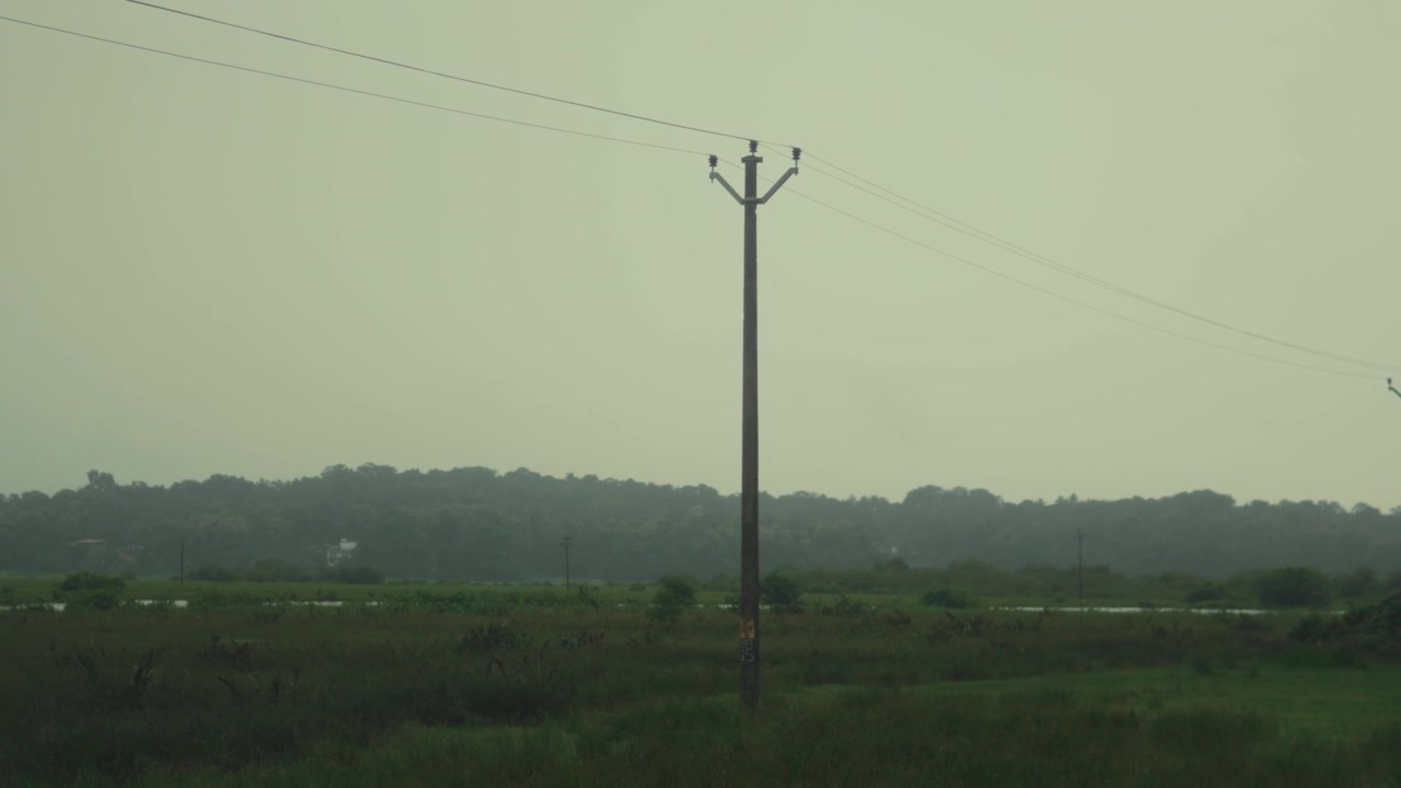 La cámara se aleja lentamente de un poste de electricidad en un tranquilo paisaje rural