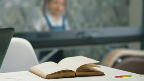 book on table against little girl playing music synthesizer