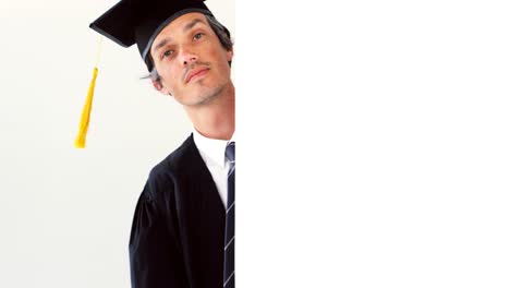 man in graduation gown touching white board