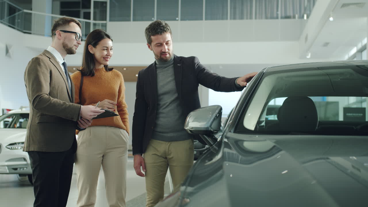 Car Salesperson Showing Car to Customers in Showroom
