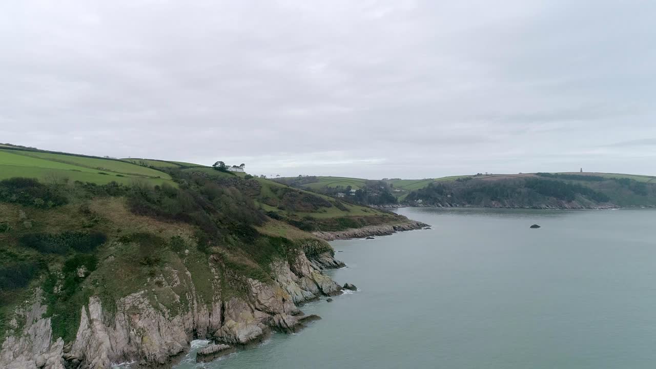 seguimiento aéreo hacia adelante sobre la costa sur de devon, apenas visible es la desembocadura del río dart.