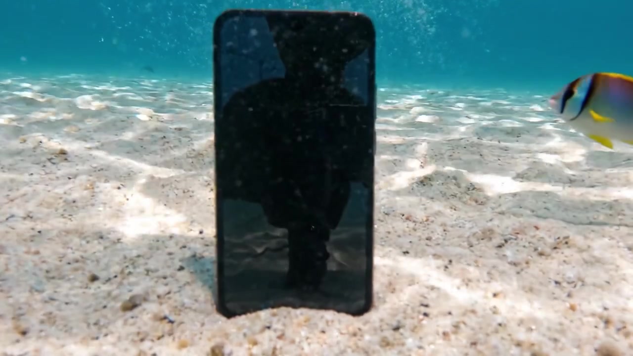 An Underwater Encounter: A Smartphone Submerged in Crystal Clear Waters Surrounded by Sparkling Sand and Air Bubbles, Capturing Nature's Serenity and Technology's Fragility