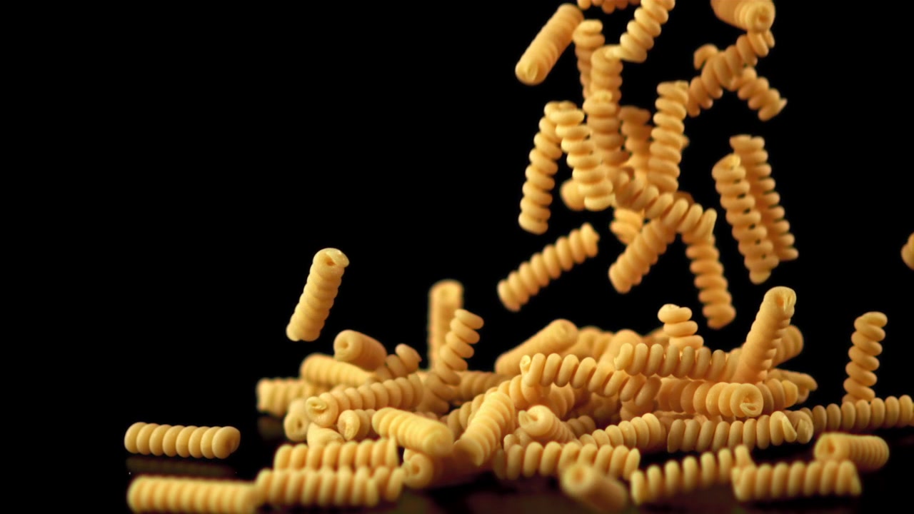 Movimento Rallentato di Pasta Fusilli Secca che Cade su Sfondo Nero